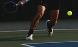 Player swinging a pickleball paddle mid-rally on an outdoor court