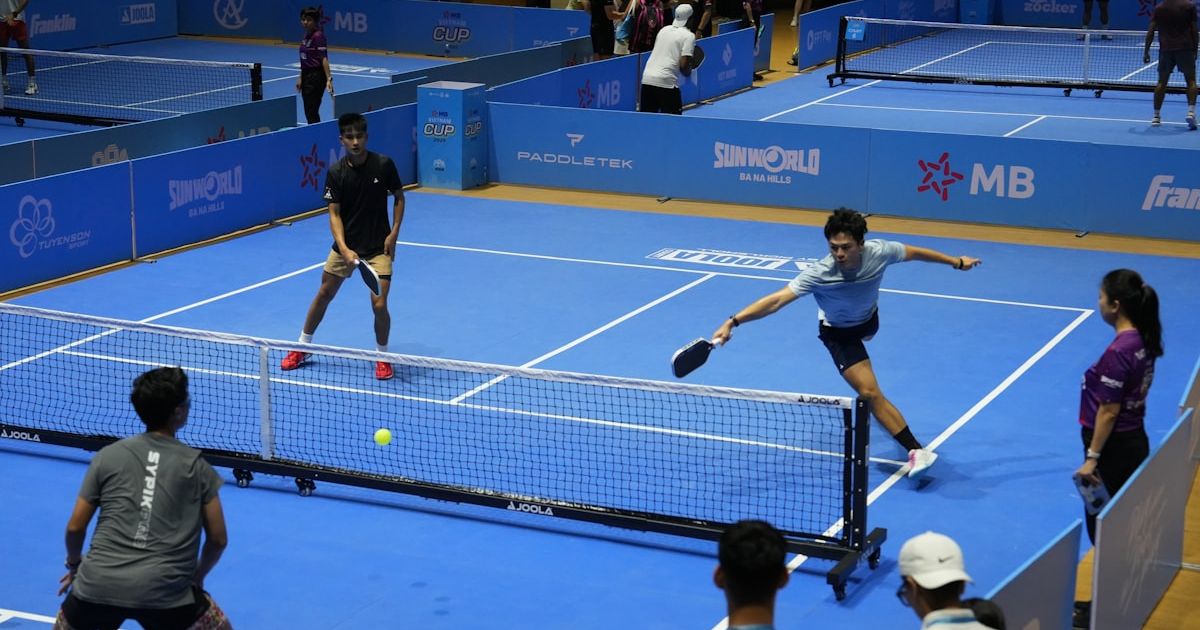 Players competing in a pickleball match on blue courts