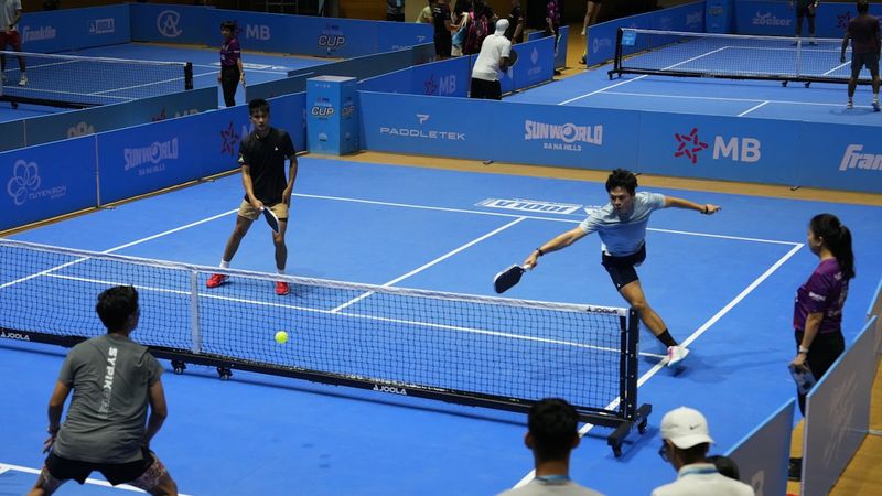 Players competing in a pickleball match on blue courts