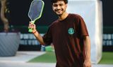 Player holding a pickleball paddle on an outdoor court